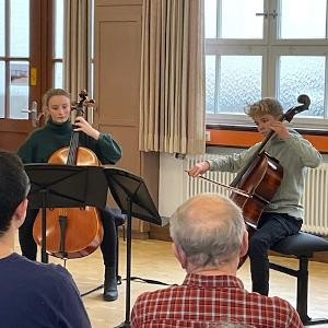 zwei Schüler spielen Cello vor Publikum