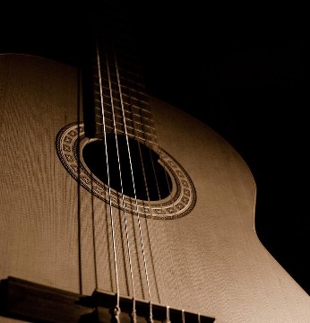 Nahaufnahme einer klasischen Gitarre in einem dunklen Raum Nahaufnahme einer klasischen Gitarre in einem dunklen Raum