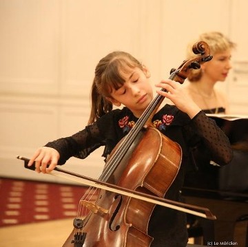 Mädchen spielt Cello, im Hintergrund ist eine Klavierspielerin Mädchen spielt Cello, im Hintergrund ist eine Klavierspielerin