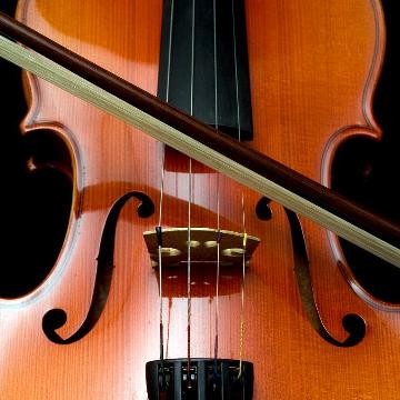 Frotale Nahaufnahme einer Geige, Geigenbogen liegt über ihr Frotale Nahaufnahme einer Geige, Geigenbogen liegt über ihr