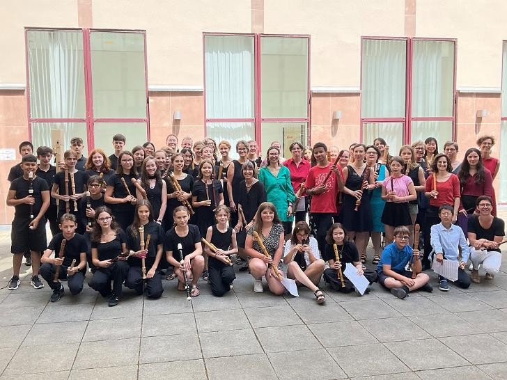 Viele Schülerinnen und Schüler stehen als Gruppe zusammen mit ihren Flöten