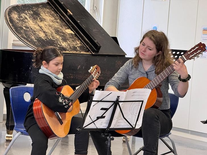 Eine Frau und ein Mädchen spielen Gitarre