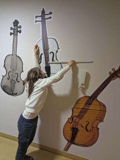 Junge tut so, als ob er ein Cello, dass an die Wand gemalt wurde, bespielen würde