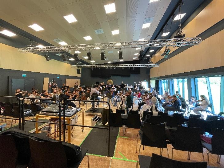 Jugendliche proben als Orchester in einem Saal. 