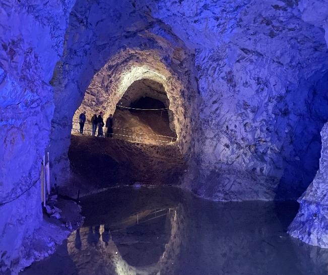 Kalkmine, Kalkhöhle, die Steine werden mit blauem Licht beleuchtet. ein unterirdischer See liegt im Vordergrund