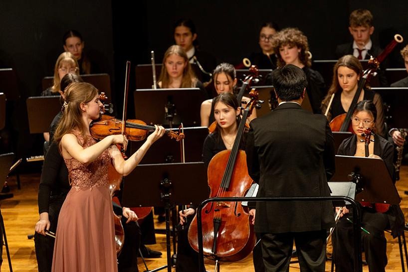 Violinsolistin spielt vor dem Orchester stehend