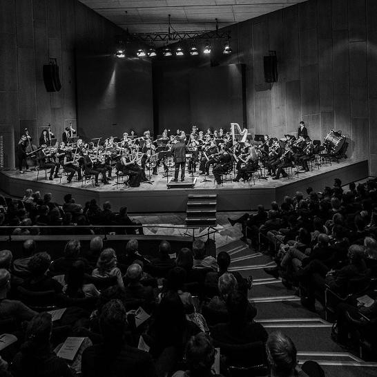 schwarz-weiß Foto, Orchester auf der Bühne vor Publikum